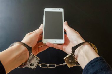 Akıllı telefonu tutarken kelepçeli bir kadın.