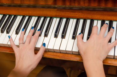 Piyanonun tuşlarına mavi tırnak cilası sürmüş kadın bir piyanistin elleri. Piyano çalan kız..