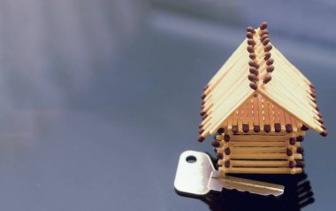 Önlerinde kibrit ve anahtarlardan oluşan bir oyuncak ev. konsept