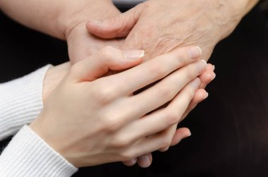 Yaşlı, yaşlı bir kadının elini tutan genç bir kızın elleri. İki kuşak kadın konsepti