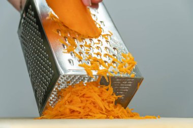 Kadın eli ızgarada, lezzetli havuç rendeliyor.