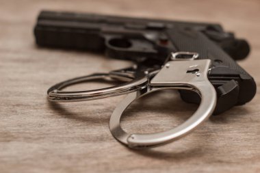 Ahşap arka planda kelepçeli siyah bir tabanca.