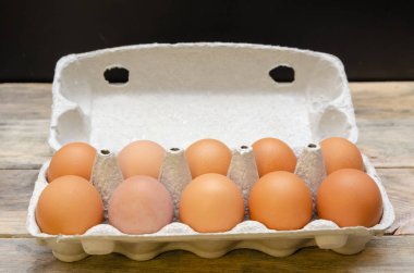 Karton bir pakette kahverengi tavuk yumurtası. Ahşap bir arka planda 10 parça. Yakın plan.