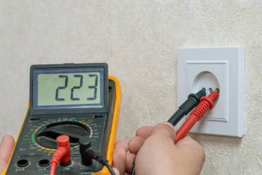 Elektrikçi dijital çokölçer kullanarak prizin voltajını kontrol eder.