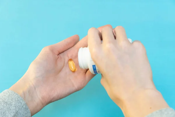 One Hand Pours Yellow Vitamin Capsules Other Hand Blue Background — Stock Photo, Image