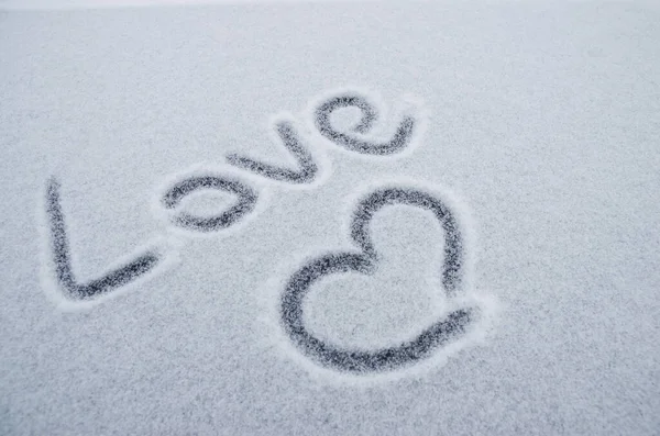 Writing text LOVE on the snow, painted heart on snow