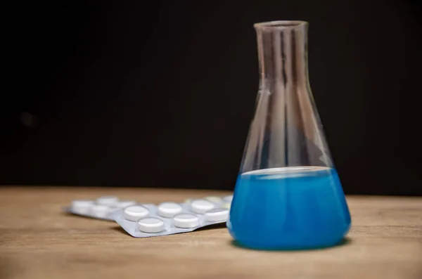 Flask Niebieskim Roztworem Pigułki Czarne Tło Zamknąć Koncepcja Medyczna Laboratorium — Zdjęcie stockowe