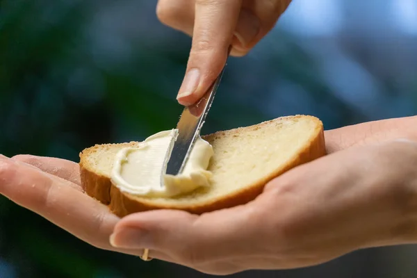 Tangan Wanita Memegang Sepotong Roti Putih Dan Menebarkan Mentega Dengan — Stok Foto