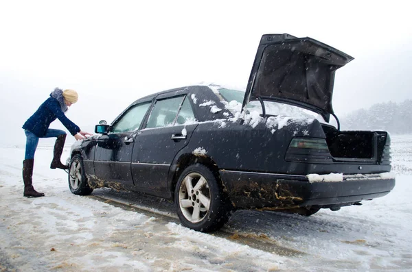Kobieta Zmieniająca Koło Czarnego Samochodu Otwartym Bagażnikiem Zimowym Śniegu Znakiem — Zdjęcie stockowe