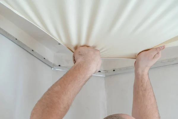 Repairers make installation of a stretch ceiling