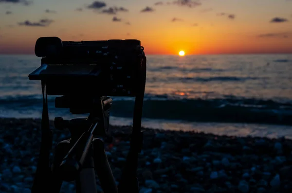 The camera stands on the shore of a pebble beach and takes pictures of a beautiful, bright, rich sunset, where the sun goes over the horizon of the sea; Batumi