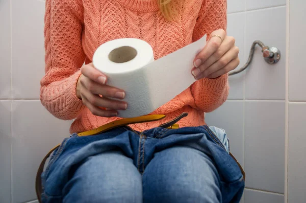 Piękna Młoda Kobieta Trzymając Papier Toaletowy Podczas Siedzenia Toalecie — Zdjęcie stockowe