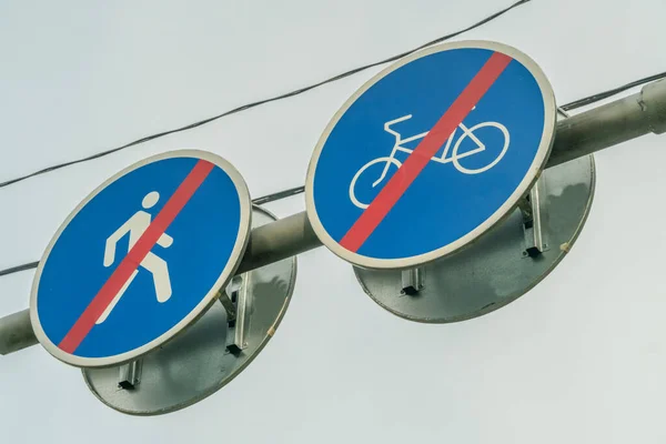空と木の枝に接近する歩行者と自転車のための2つの道路標識は ドライブとパスが終わったことを示しています — ストック写真