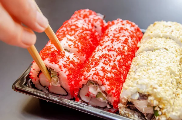 Chica Toma Sushi Rojo Con Palillos Madera Caja Sobre Fondo — Foto de Stock