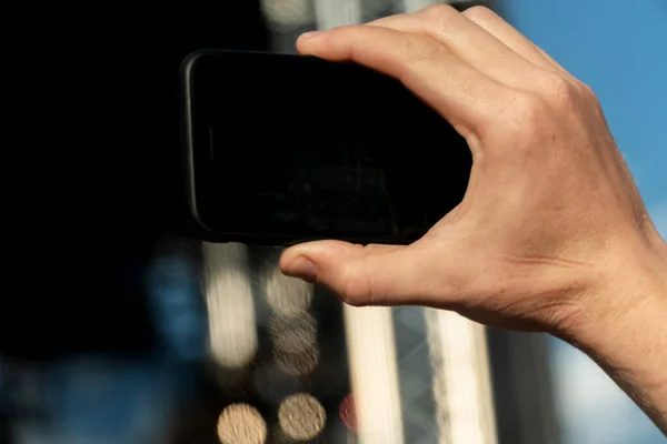 Hand holding a smartphone with a black screen and takes a close-up of what is happening