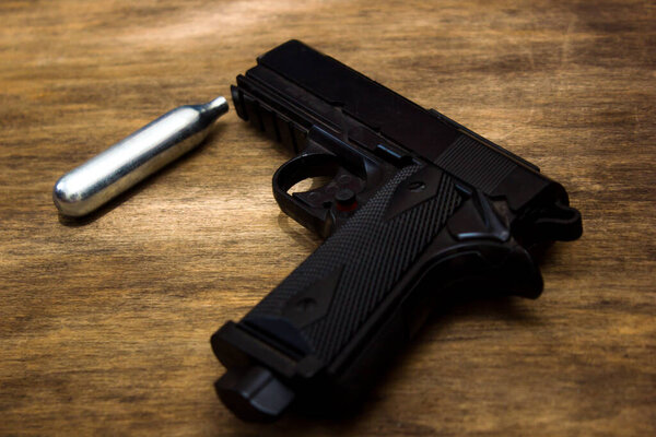 handgun with a bullet on wooden background