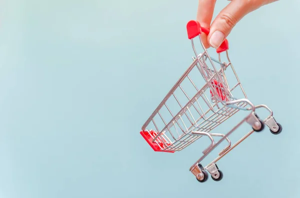 Mano Della Donna Tiene Carrello Della Spesa Uno Sfondo Blu — Foto Stock