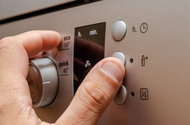 Adamın eli şık siyah bulaşık makinesi kontrol panelinde.