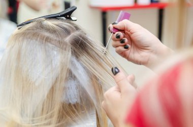 Kuaför saç boyamak için saç tellerini dağıtır.