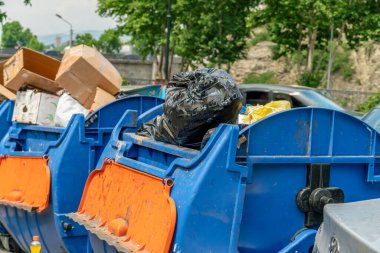 Çöplerle dolu mavi çöp tenekeleri