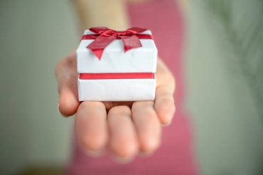 Uzamış elleri ve elinde bir kutuyla hafif bir arka planda izole edilmiş bir kız, boşluğu kopyala