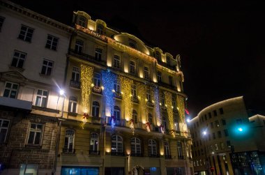 Kış mevsimsel tatilleri boyunca Avrupa şehir caddesinde ışık çelengi ile süslü bir bina.