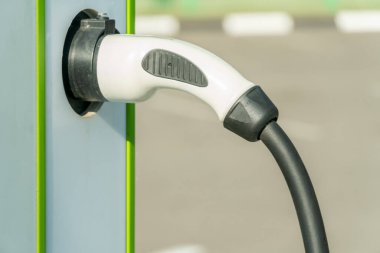 Şehrin caddesinde şarj istasyonu elektrikli arabasıyla park etmek. Araba şarj kablosunun kapatılması