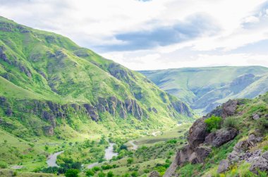 Vardzia mağara manastırının panoramik manzarası. Manastırdan nehir vadisine ve güneşli bir yaz gününde yeşil yamaçlara bakın.