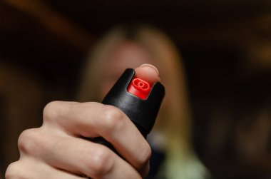 Sarışın kadın nefsi müdafaa için biber gazı tutuyor.