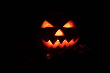 Tamamen karanlıkta parlayan gözleri ve ağzı olan bir balkabağı. Güzel Cadılar Bayramı geçmişi, konsept.