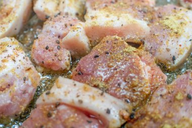 Baharatlı domuz eti parçaları tavada yakın planda kızartılır.