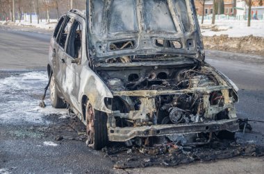 Güneşli bir kış gününde yolda yanmış bir araba.