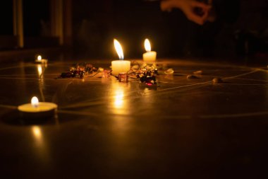 Pentagram yere boyanır, mumlar yakılır, boncuklar yerde yatar, kabuklar dağılır. Okült ve esrarengiz sembollerle büyü kavramı.