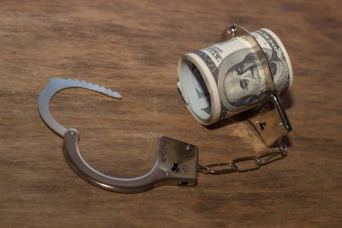Kelepçe ve para ahşap masada. Dolar. hücum kavramı