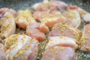 Baharatlı domuz eti parçaları tavada yakın planda kızartılır.