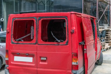 Güneşli bir günde arka camları olmayan kırmızı minivan.