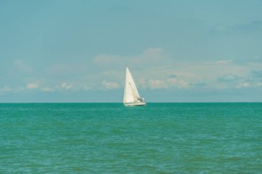 Karadeniz 'de beyaz yelkenli yat güneşli bir havada bulutlarla gökyüzüne karşı.
