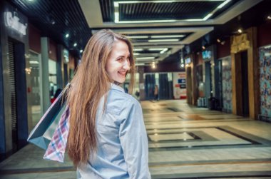 Mutlu kız alışveriş merkezine omuzunda alışveriş yapmaya gider.