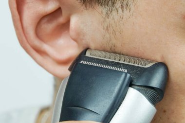 Adam favorilerini elektrikli jiletle traş ediyor.