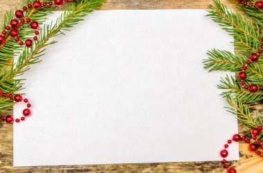 Noel ağacı dalları ve kırmızı boncuklar ile ahşap arka planda beyaz yaprak fotokopi alanı ile kapanır. Güzel Noel arkaplanı veya tebrik kartı