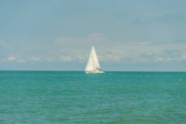 Karadeniz 'de beyaz yelkenli yat güneşli bir havada bulutlarla gökyüzüne karşı.