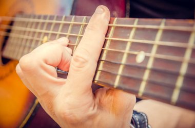 Akustik gitar çalan bir gitaristin elinin yakın çekimi. Gitaristin eli, akustik gitarın yakın planında.