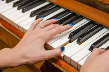 Piyanonun tuşlarına mavi tırnak cilası sürmüş kadın bir piyanistin elleri. Piyano çalan kız..