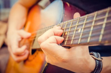 Akustik gitar çalan bir gitaristin elinin yakın çekimi. Gitaristin eli, akustik gitarın yakın planında.