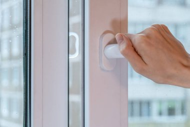 Kadın eli bulutlu bir günde camına damla damlatan bir pencere açar.