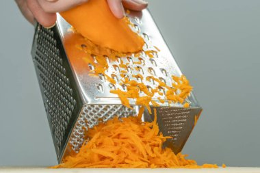 Kadın eli ızgarada, lezzetli havuç rendeliyor.