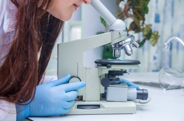 Bilimadamı laboratuvardaki mikroskopu inceliyor, öğrenci.