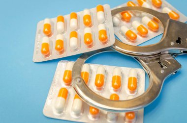 Kelepçe ve mavi arka planda bir sürü hap.