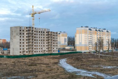 İnşaat halindeki çok katlı bir binanın yanında vinç var. Yakınlarda zaten çok katlı binalar var.