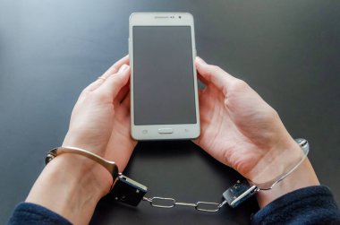 Akıllı telefonu tutarken kelepçeli bir kadın.